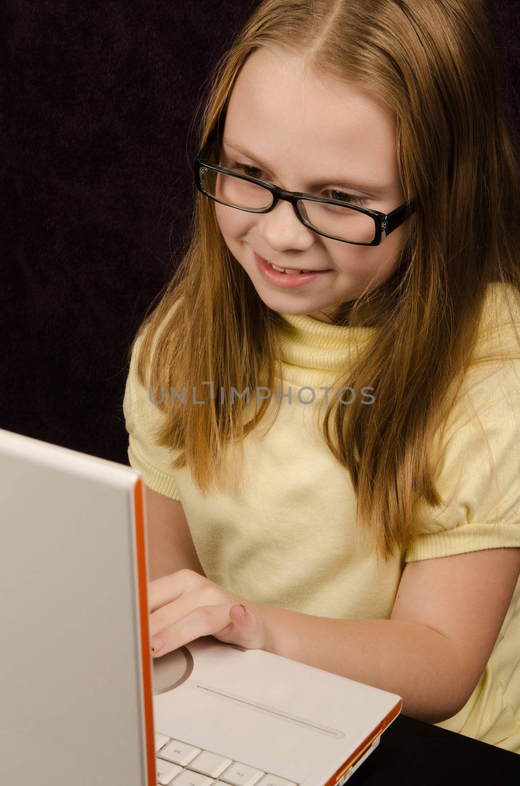Little girl  looks at laptop computer and having fun