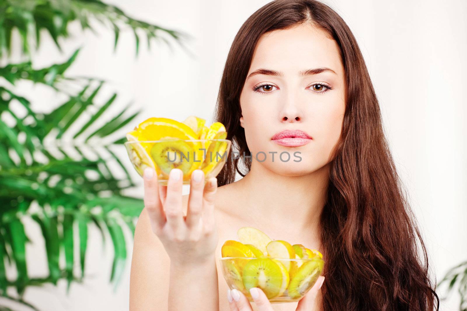 Woman holding two bowl full of fruit in front of palm tree