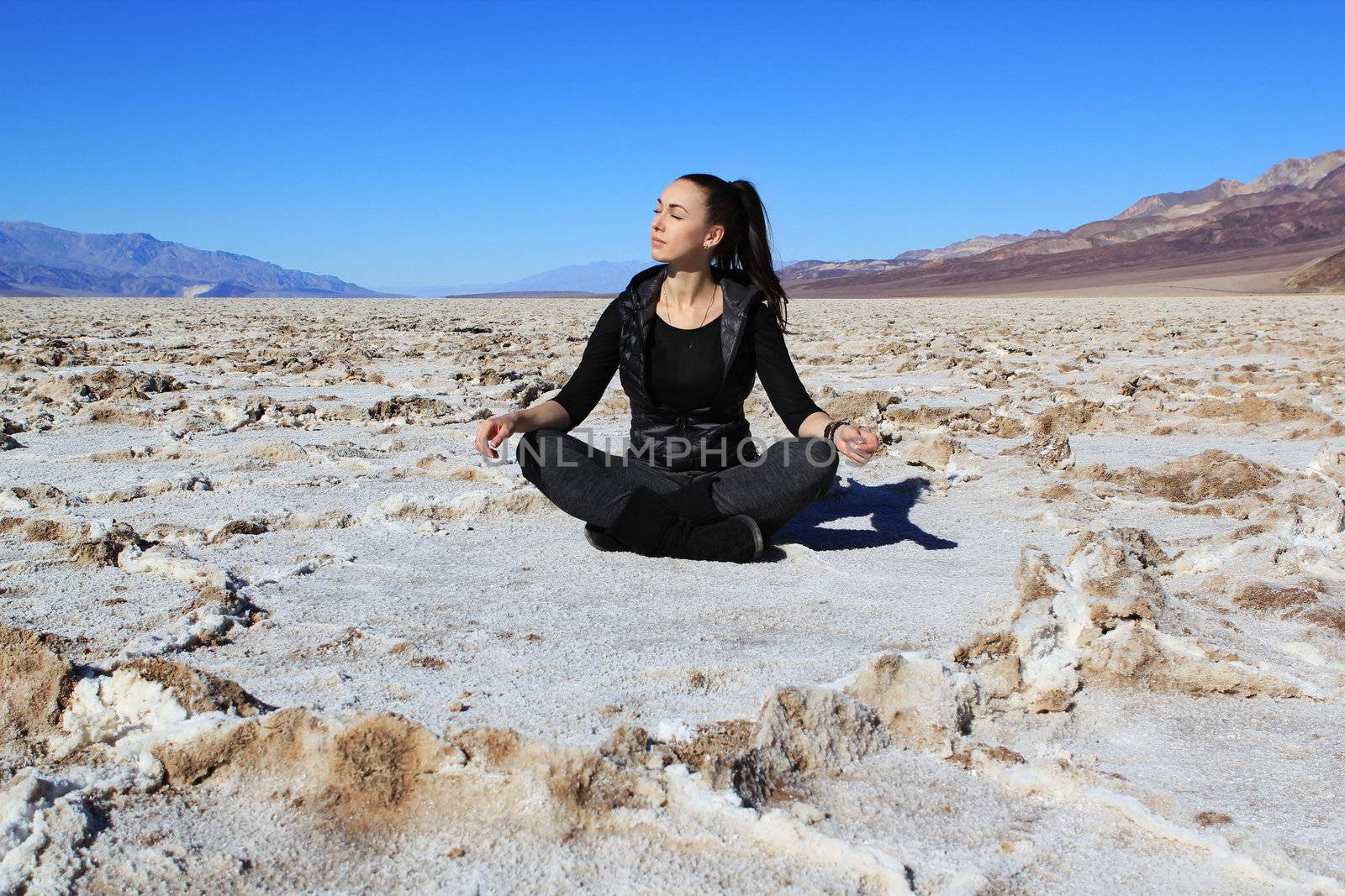 The beautiful girl sits in Bad water Salt lake at Death Valley