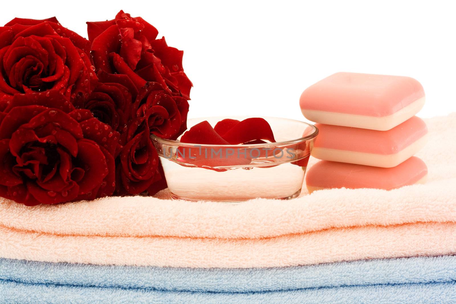 A bouquet of red roses and pink soap on towels