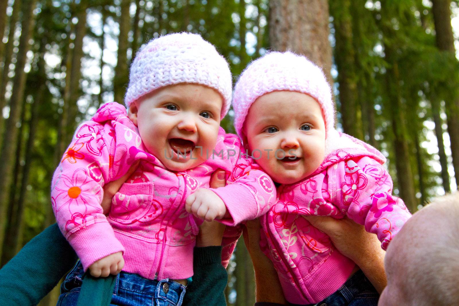 These two twin girls are having a fun time playing with their parents as they are lifted high in the air.