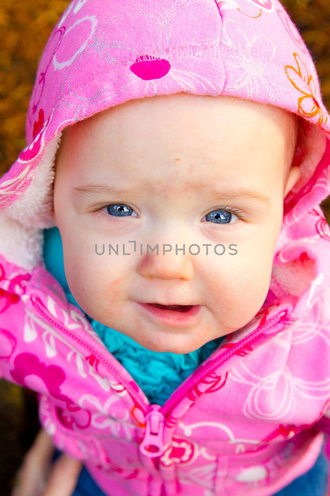 A young infant girl in pink is photographed outdoors for this child portrait.