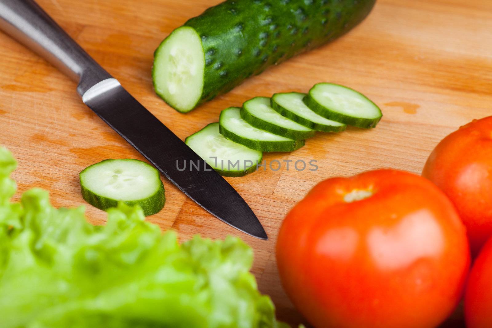Vegetables (tomato, cucumber, salad) on a wooden table