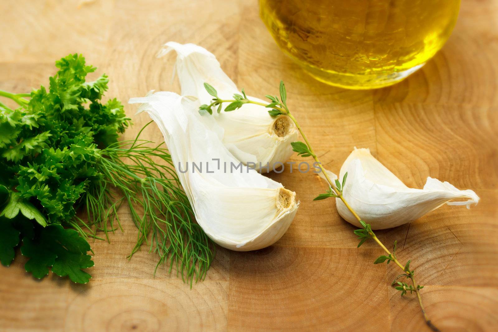 Garlic with dill, thyme and parsley with olive oil on wooden board