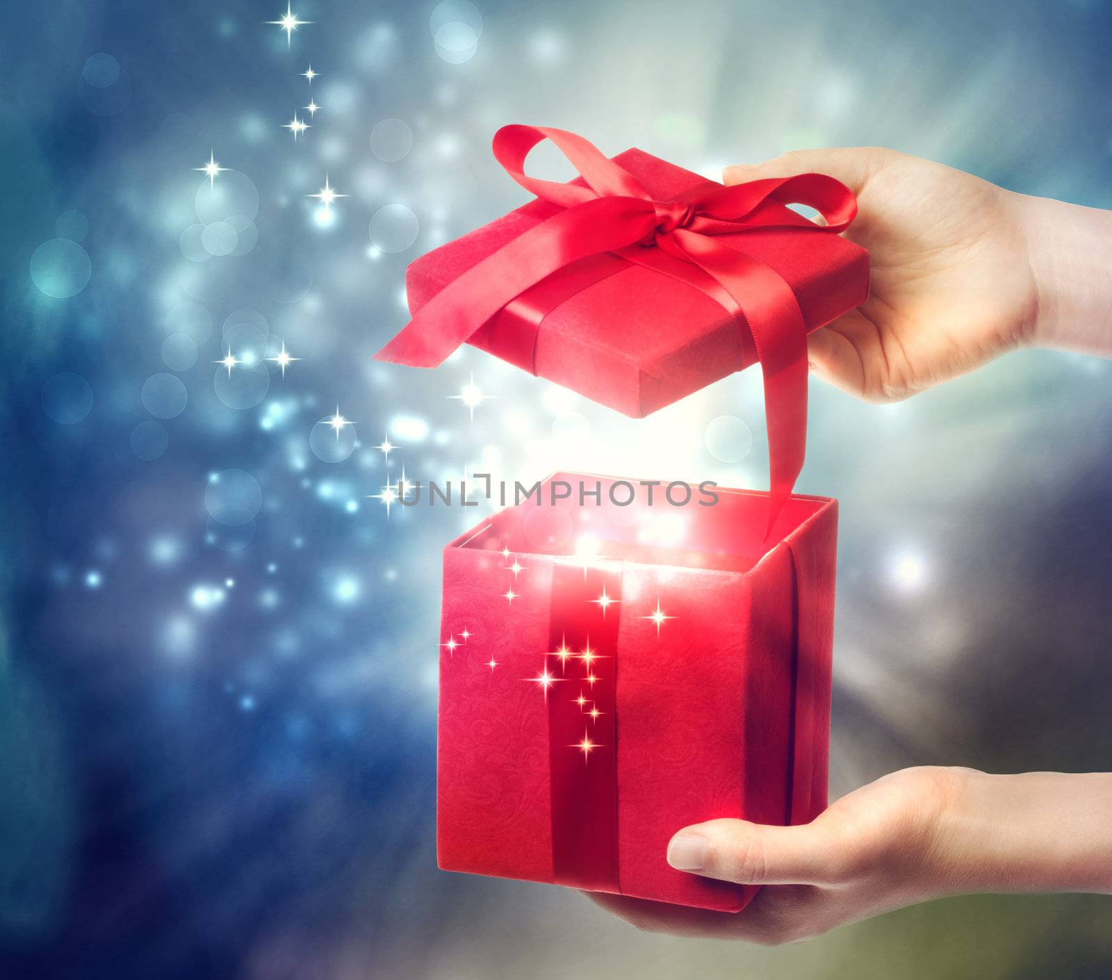 Woman holding a red gift box on a blue holiday lights background 
