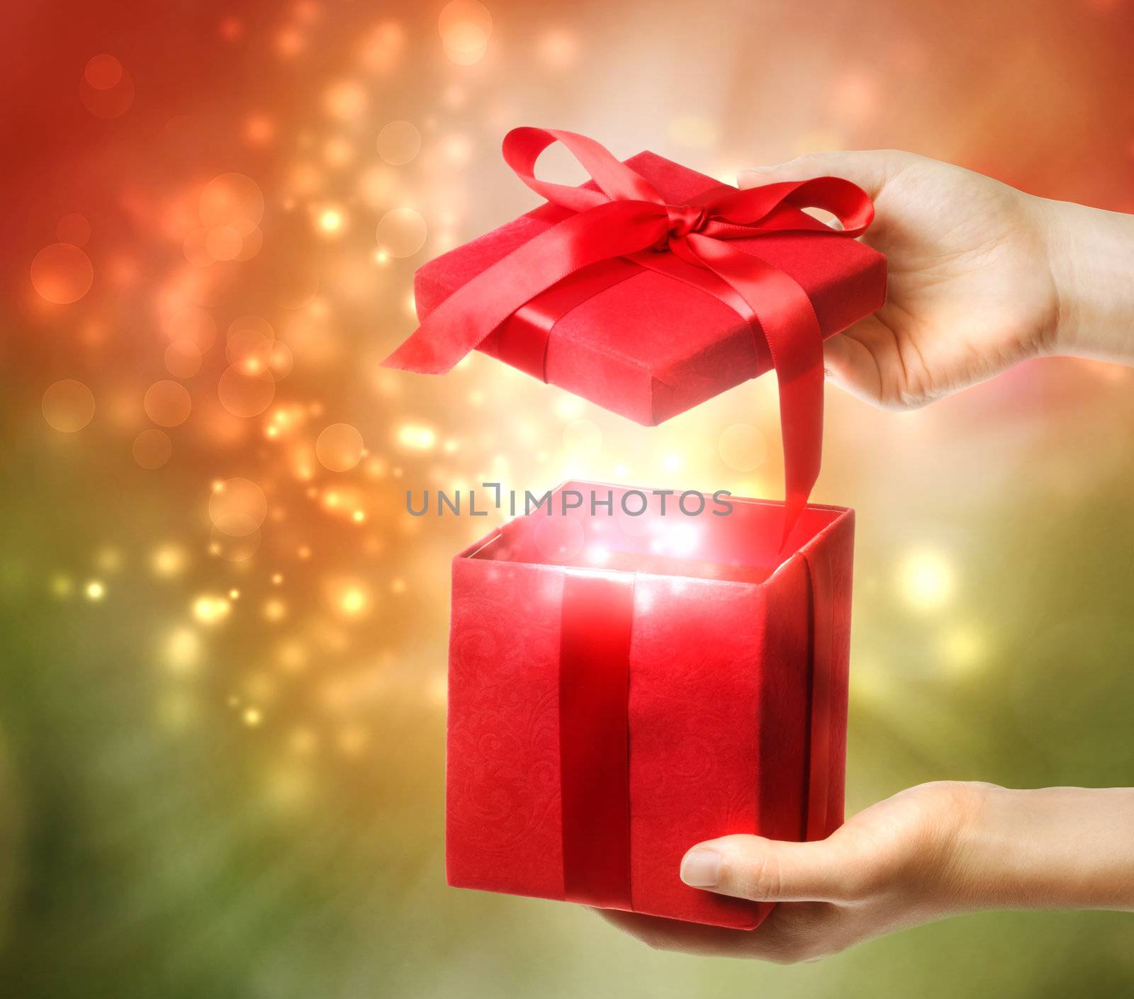 Woman holding a red gift box on a bright holiday lights background 