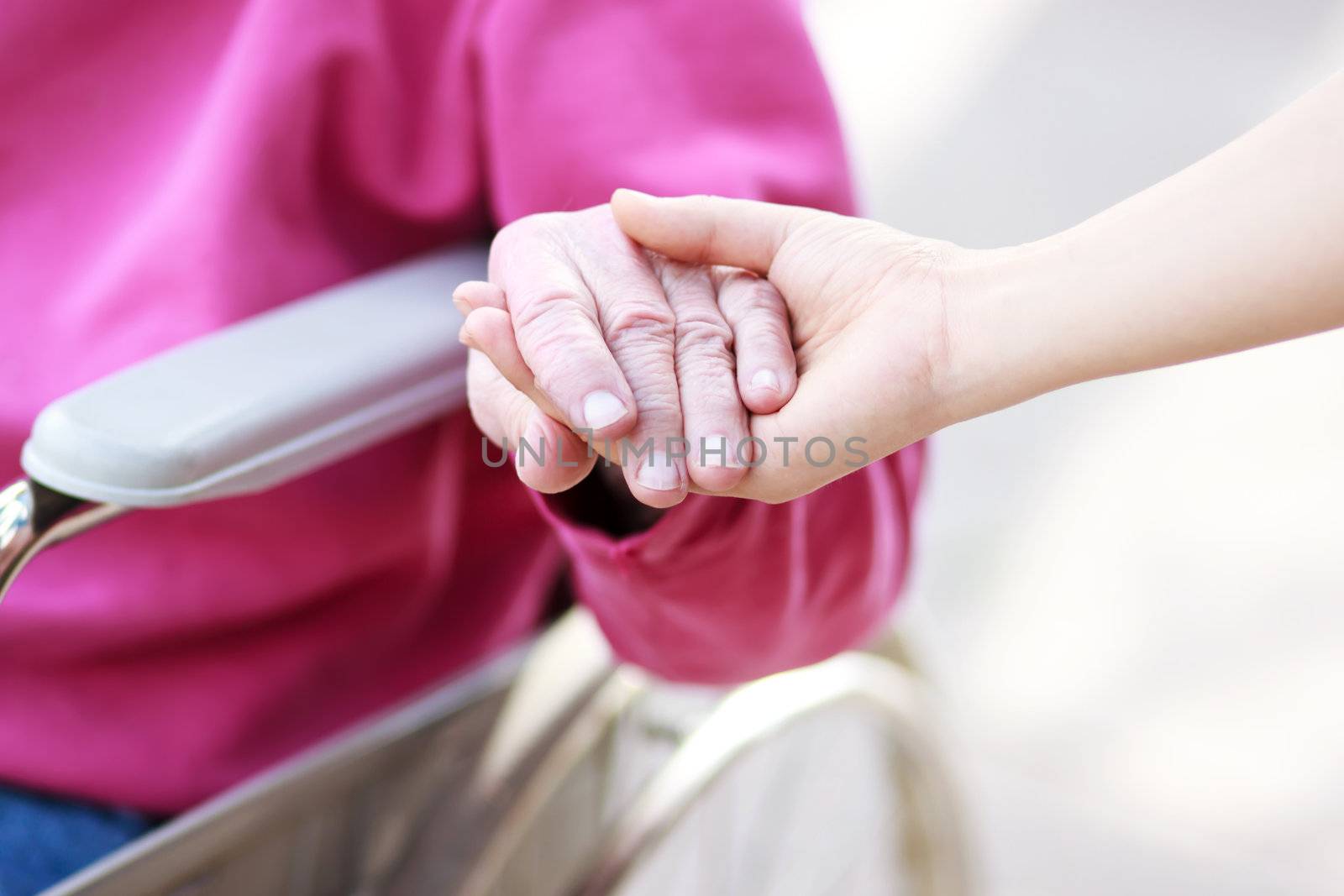 Senior Lady in Wheelchair Holding Hands with Caretaker