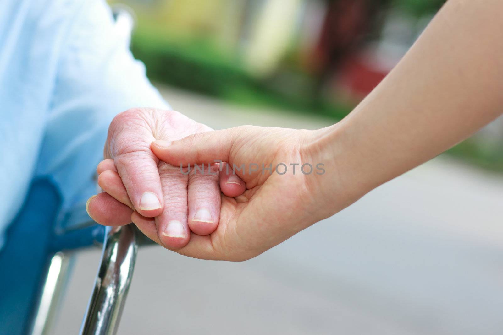 Senior women in wheelchair holding hands by melpomene