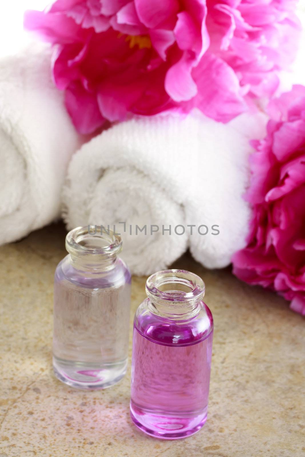 Aroma oil with pink peony flowers and towels
