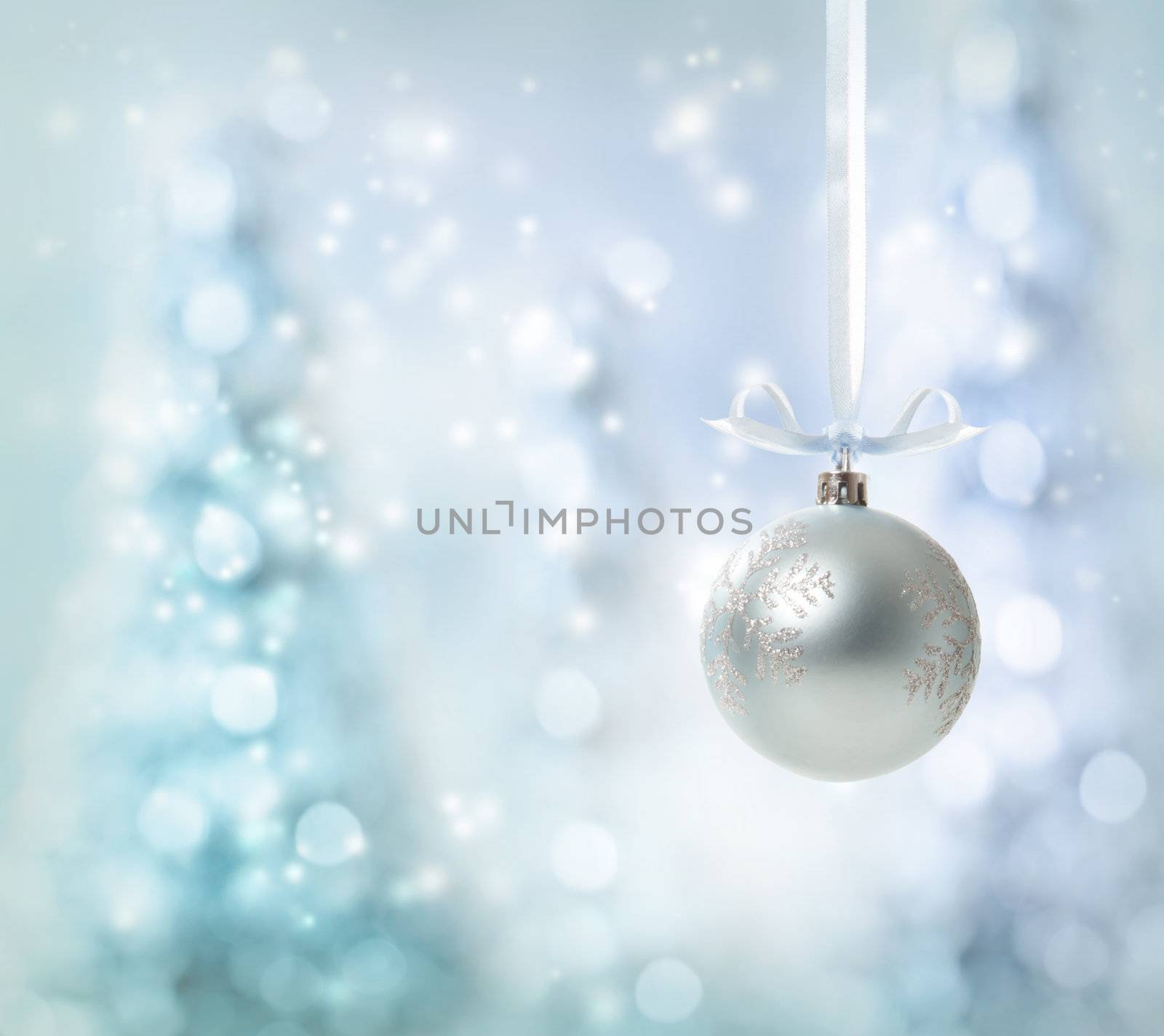 Silver Christmas Ornament over glowing tree background