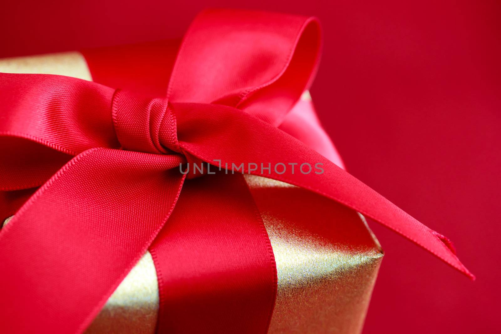 Gift box with red ribbon on red background
