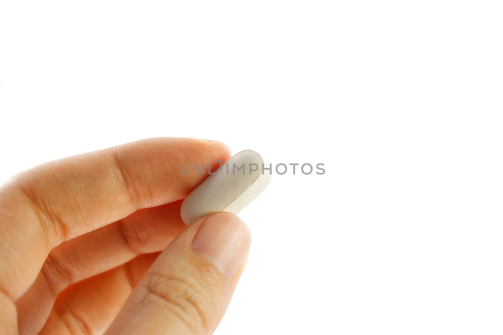 Hand holding a white pill isolated on white background