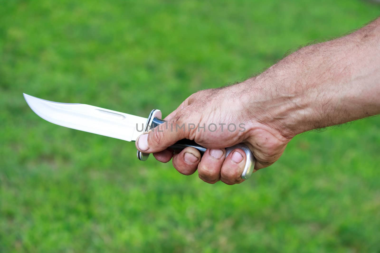 Man holding dagger over green lawn background