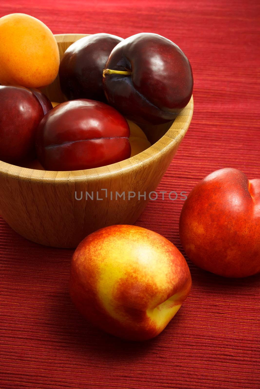 Juicy nectarines, plums and apricots on red background