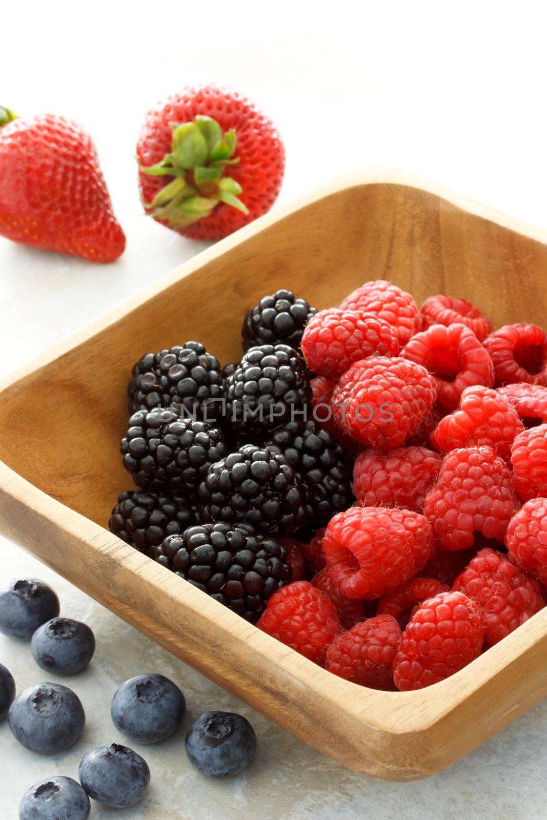 Assorted fresh berries in wooden bowl
