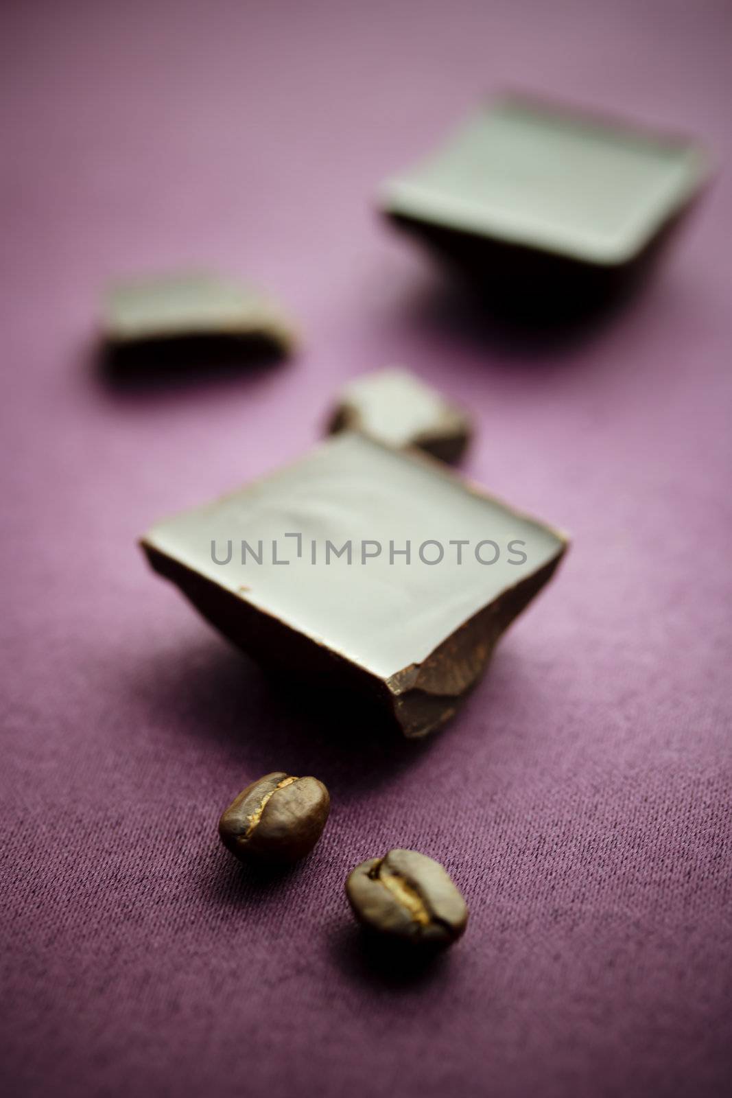Chocolate with coffee beans on violet tablecloth