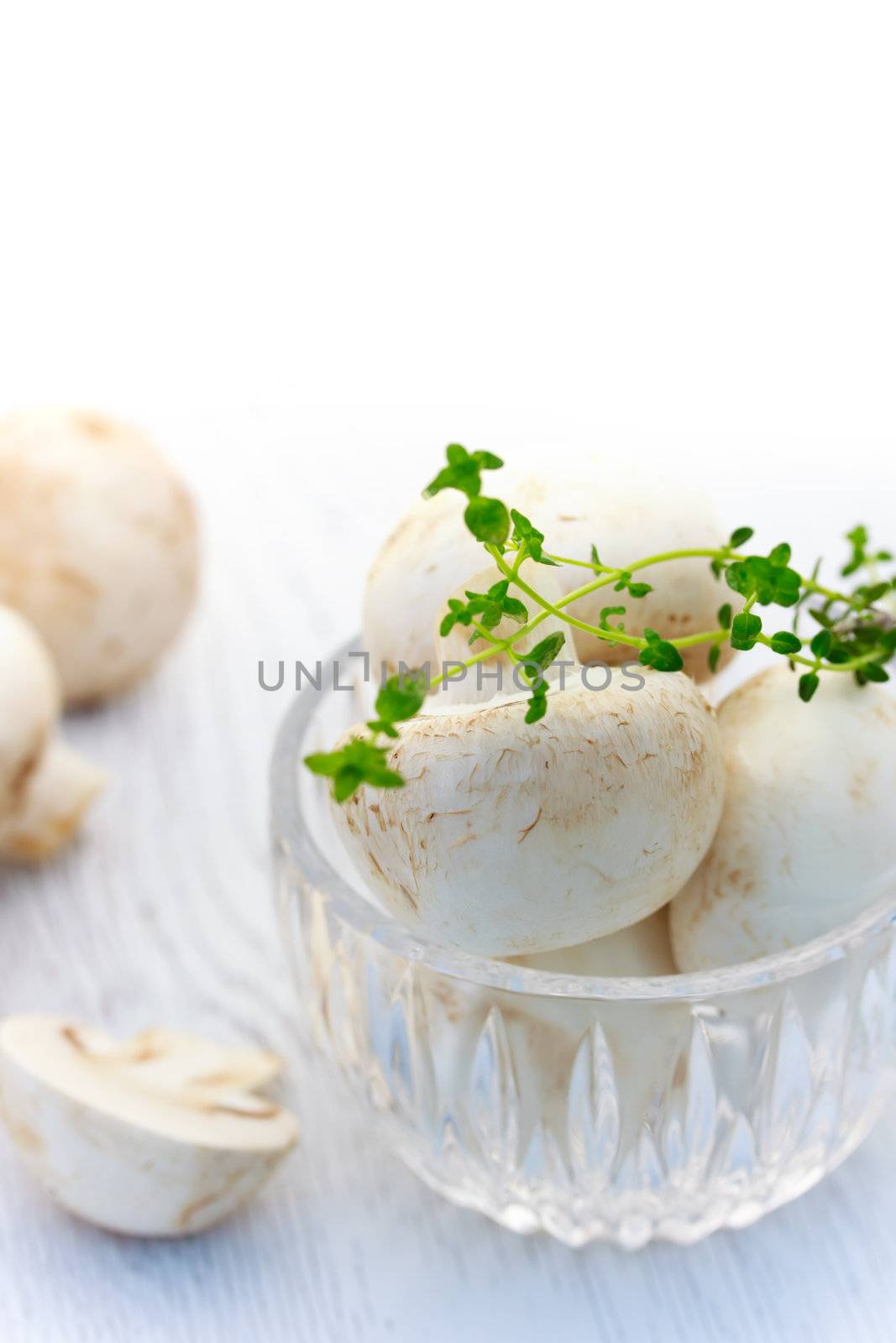 Mushrooms in the glass cup with thyme over white background