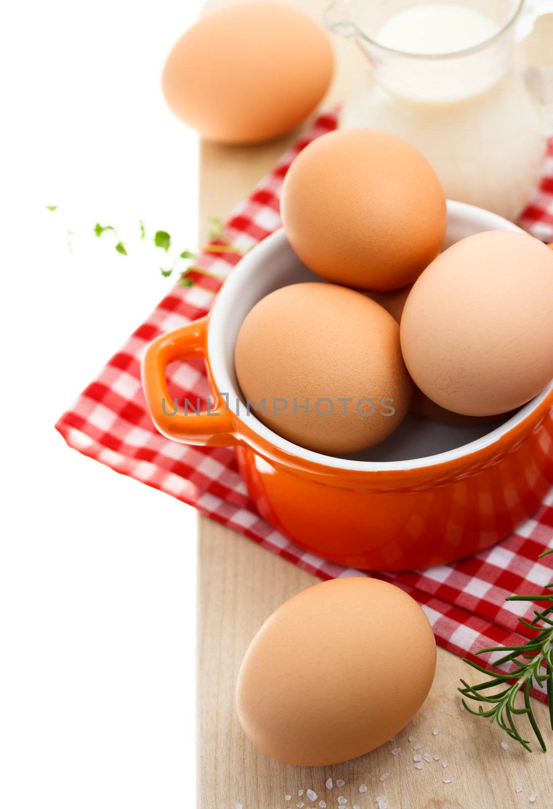 Fresh brown eggs with milk on red gingham checked tablecloth