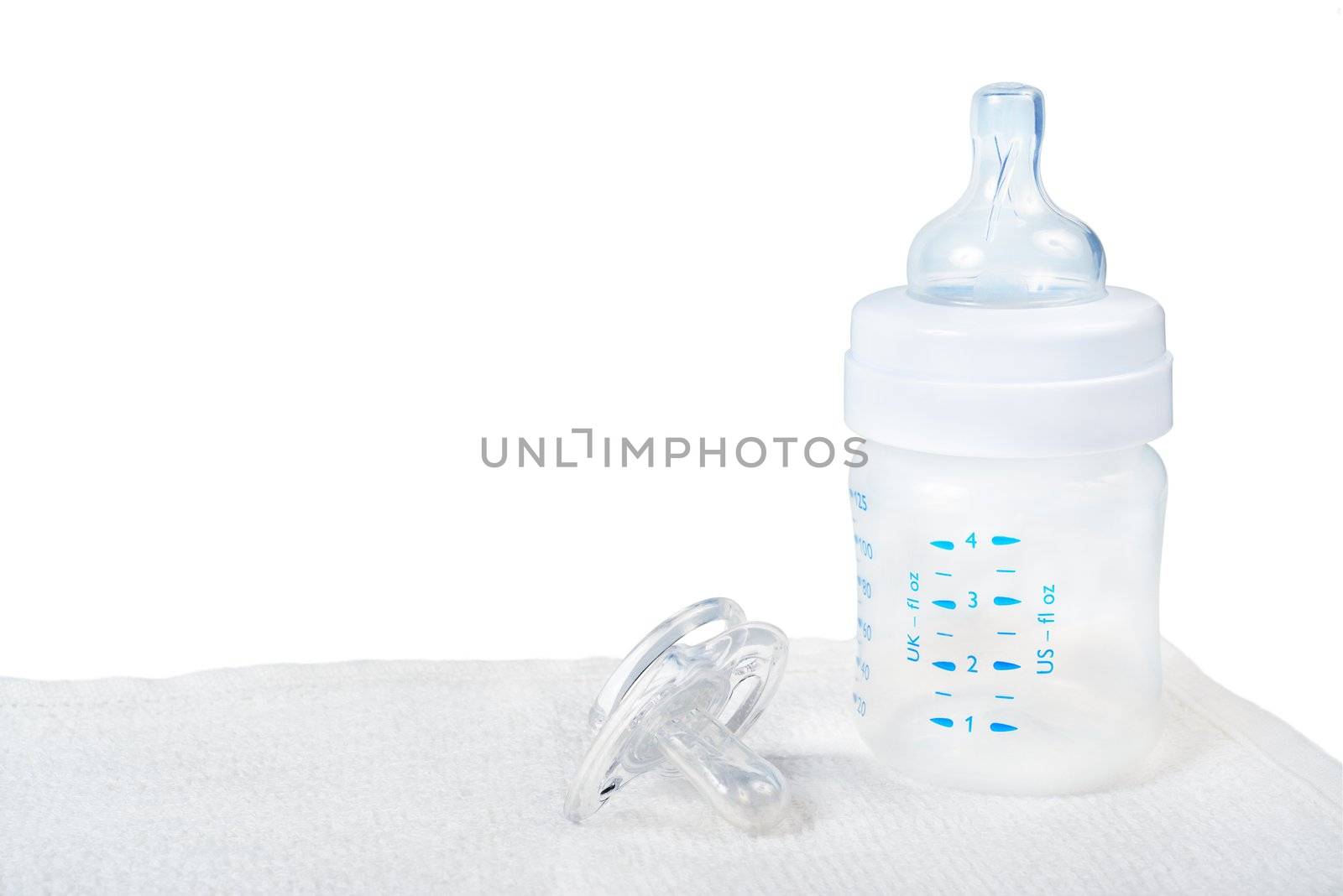 Baby bottle and pacifier on towel.