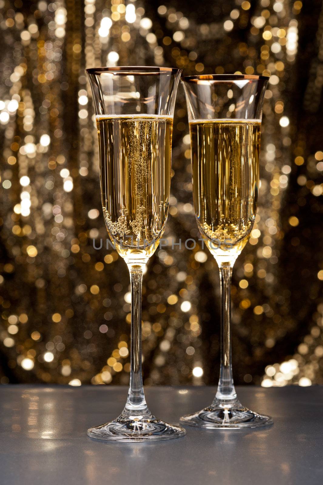 Champagne glasses in front of gold glitter background
