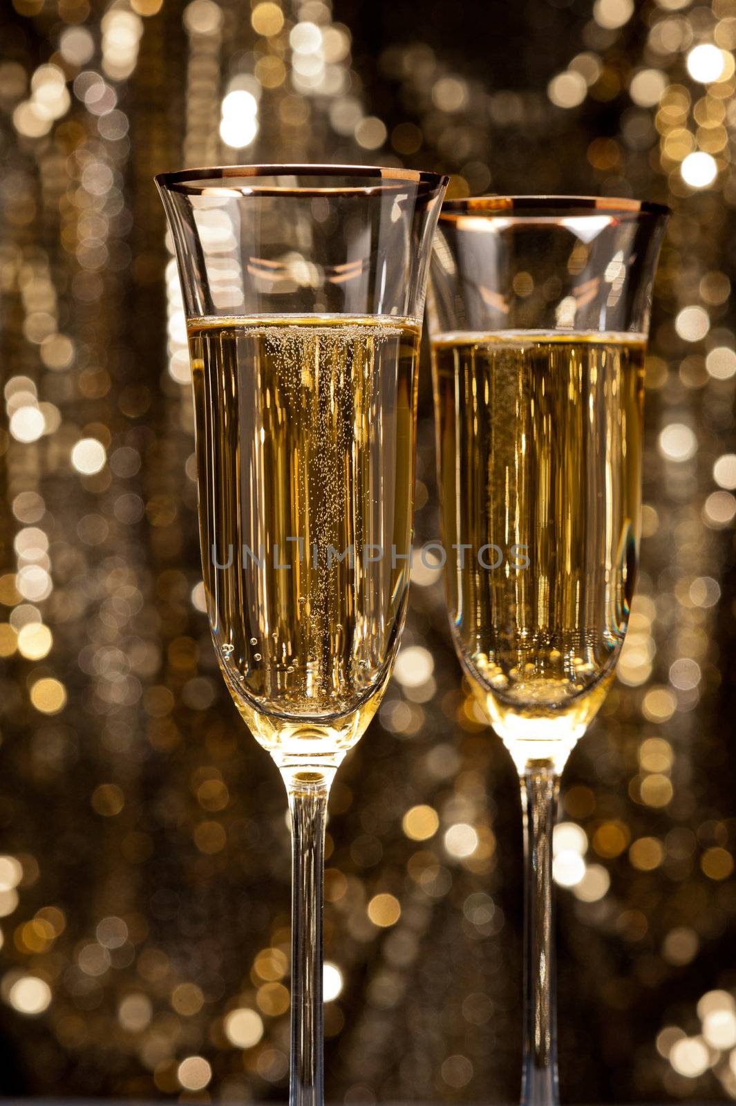 Champagne glasses in front of gold glitter background