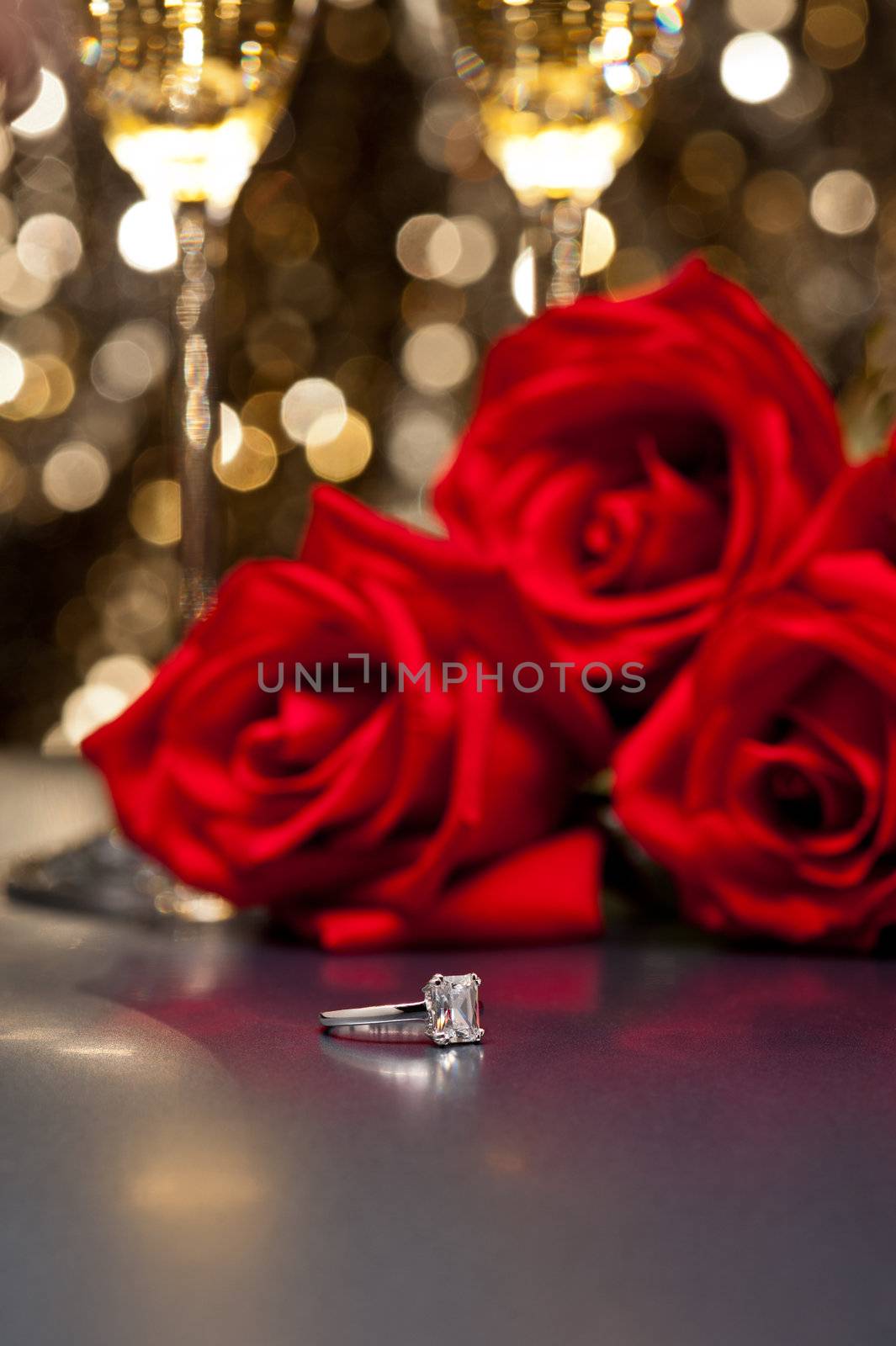 Jewelry ring and roses in front of a gold glitter background
