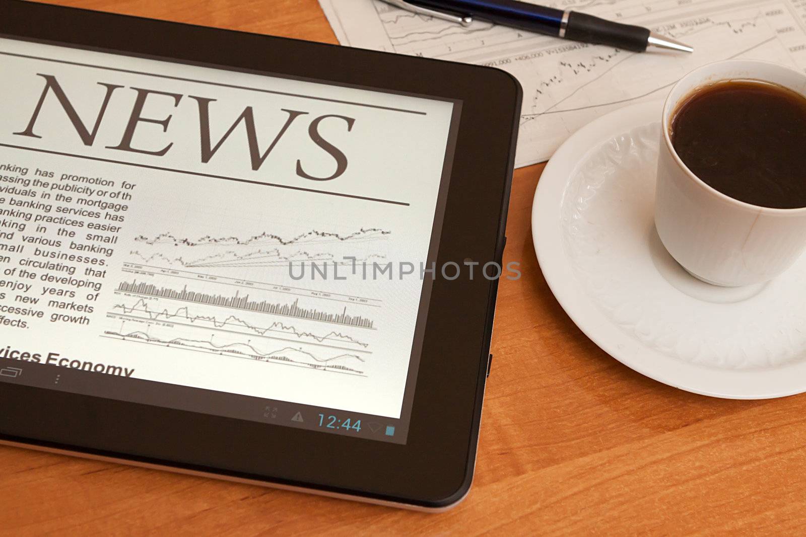 Tablet PC shows latest news on screen, which lying on work place. 