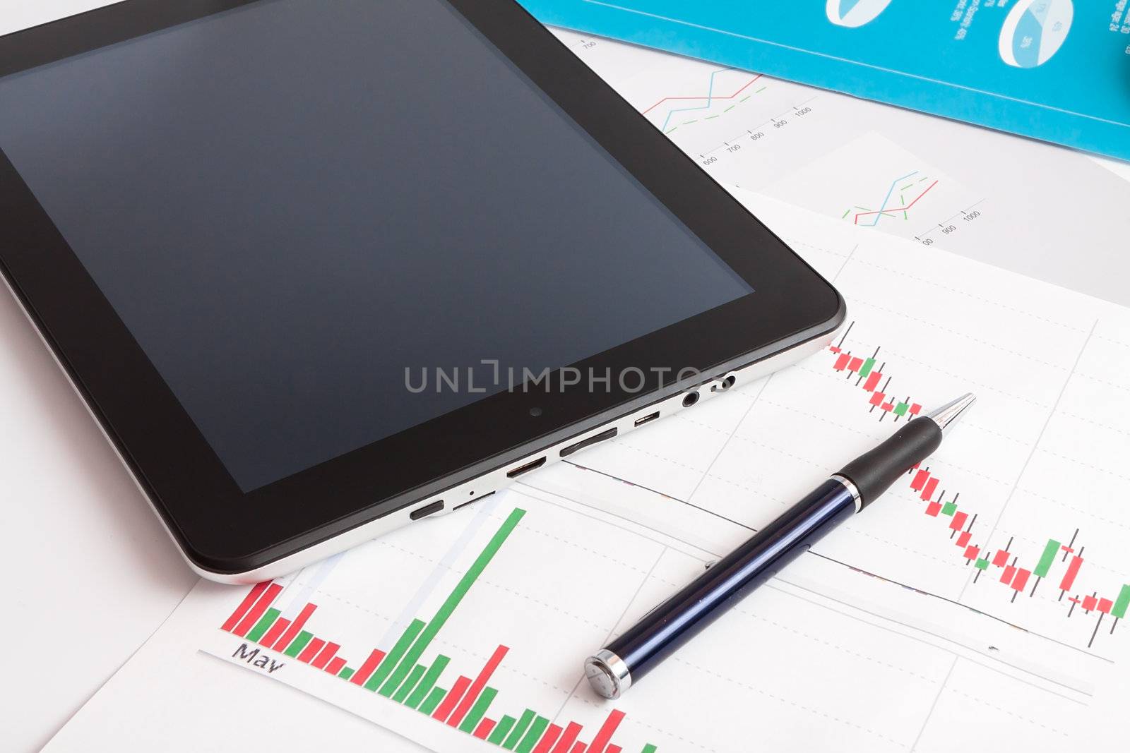 Desktop in stock exchange office with a tablet pc showing stock market chart. 