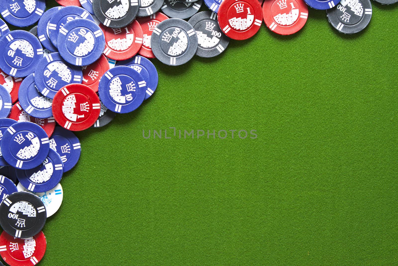 Colorful gambling chips on green felt background with copy space