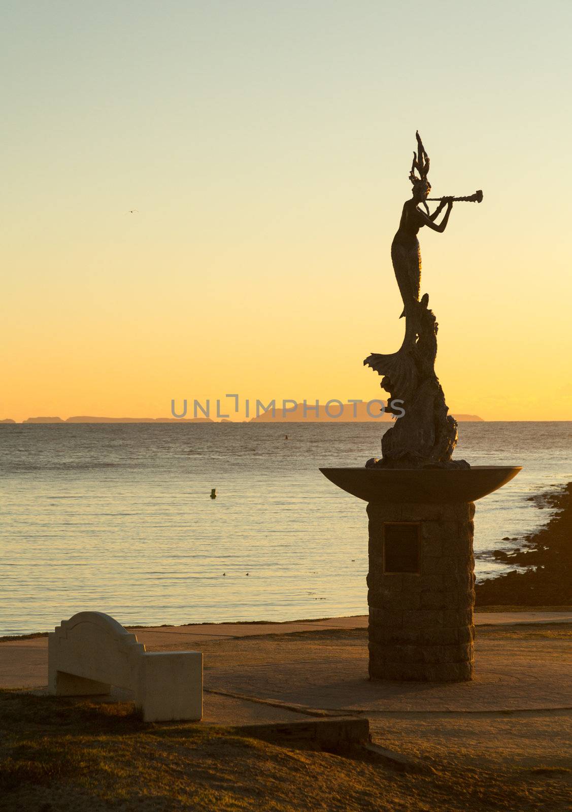 Mermaid statue playing flute by unknown artist at entrance to Ventura Harbor