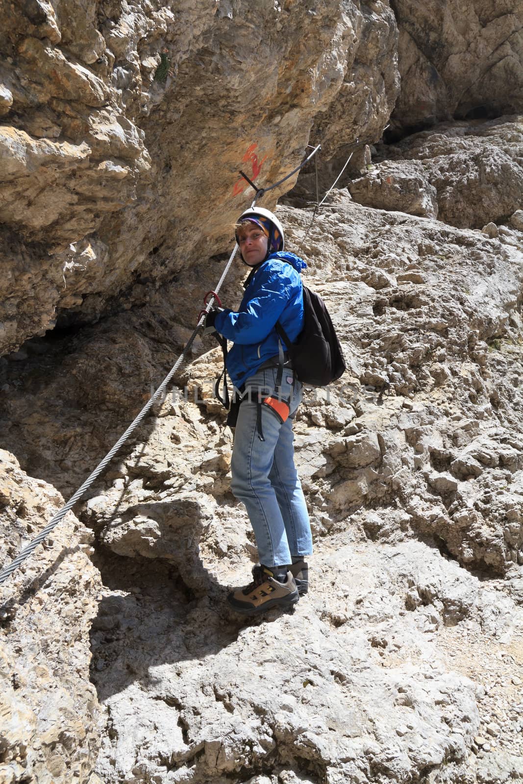 	female climber ascending rocks on equipped pathway, Italian Dolomites