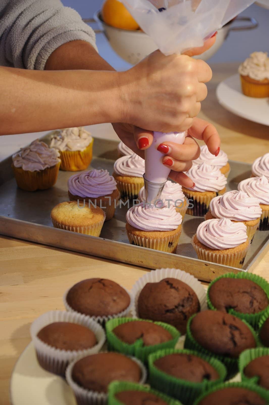 Nice girl hand decorating some tastefully cupcakes