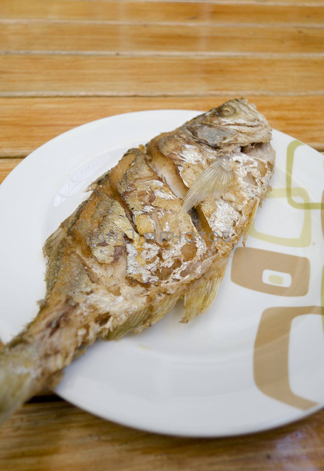 Fried fish on white dish by siraanamwong