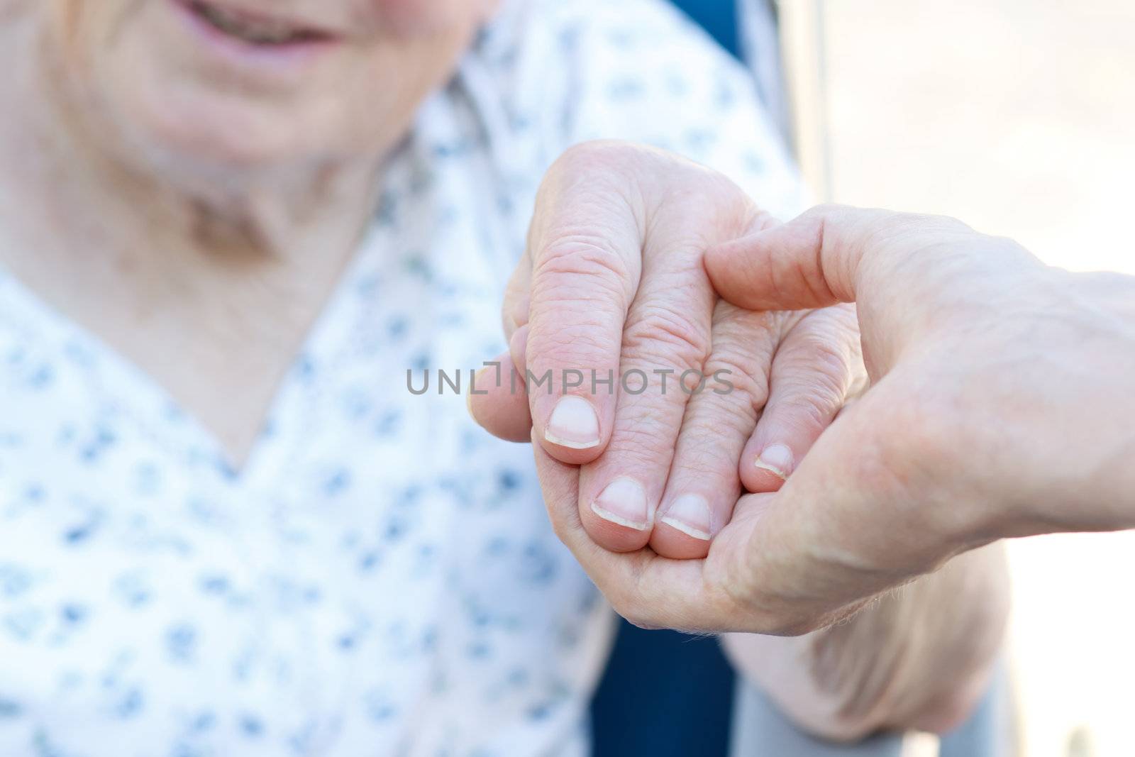 Senior woman in wheelchair holding hands with caretaker