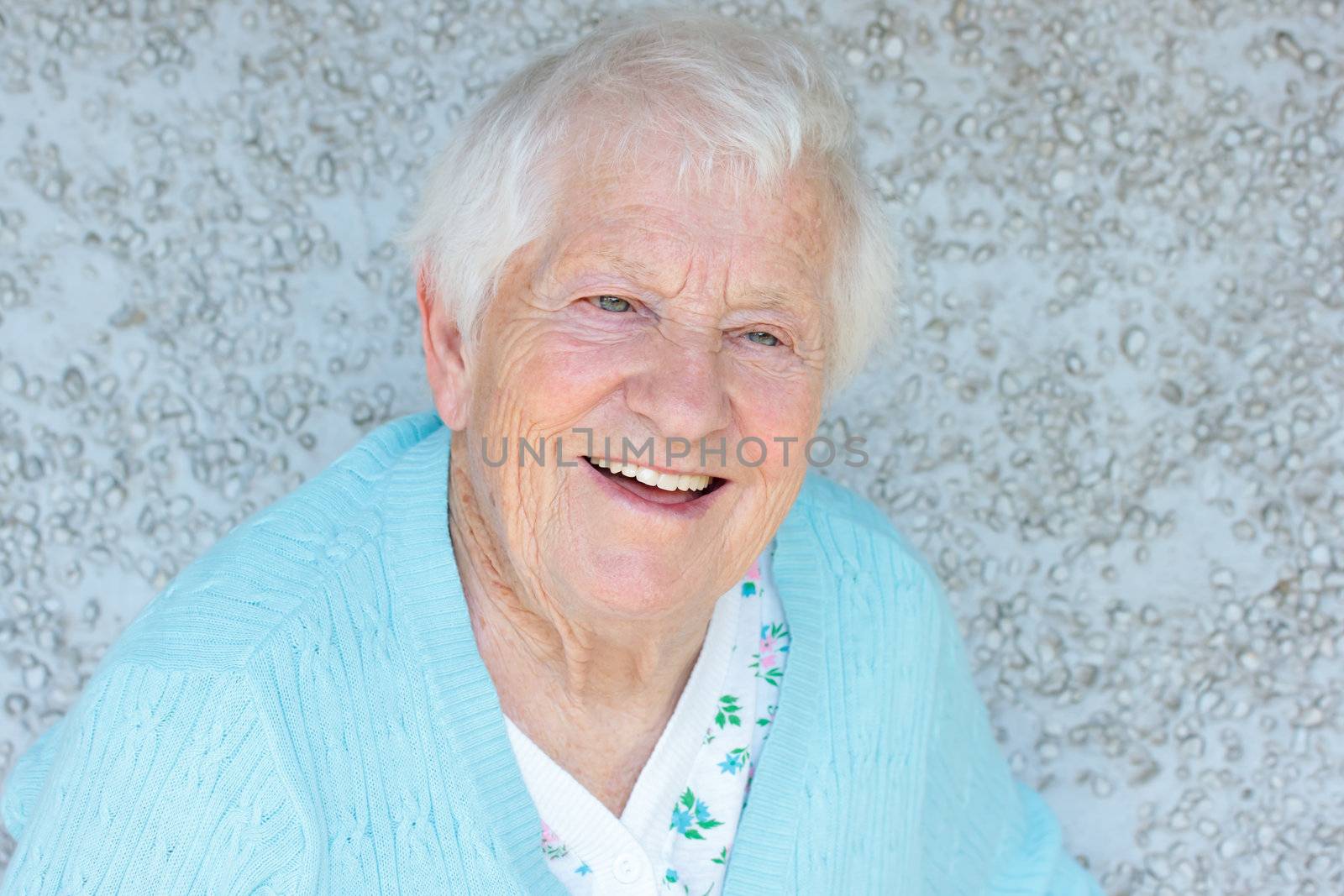 Happy senior lady smiling in front of light blue wall