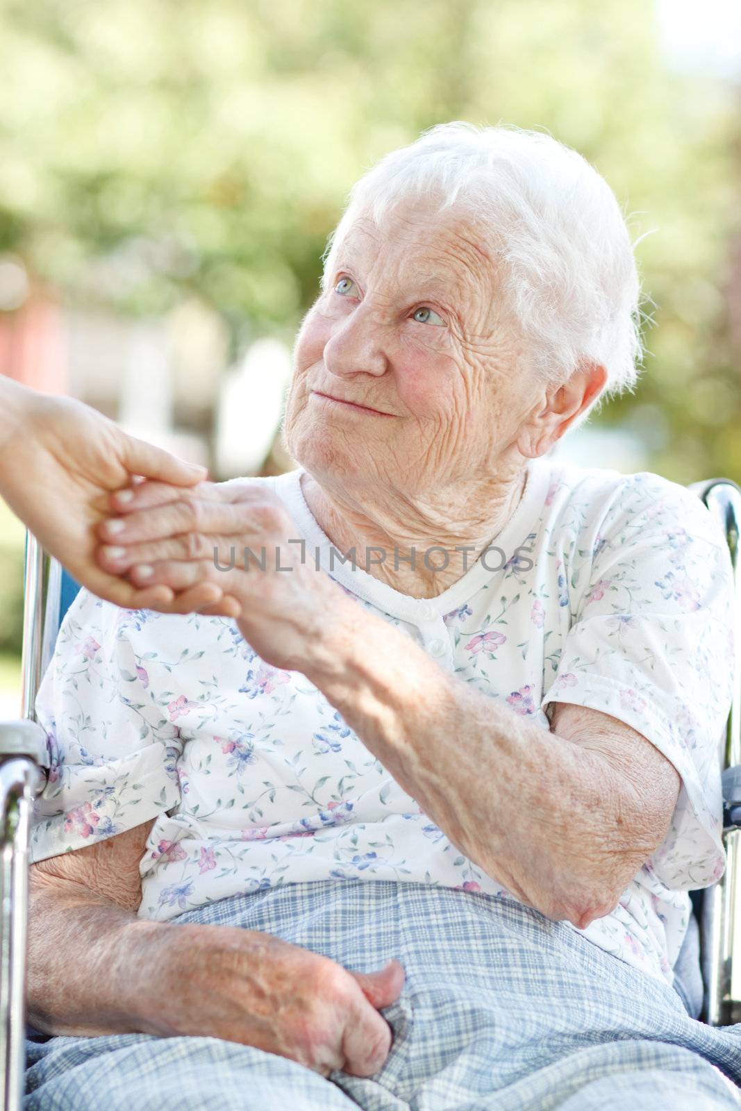 Happy senior woman holding hands with her caretaker