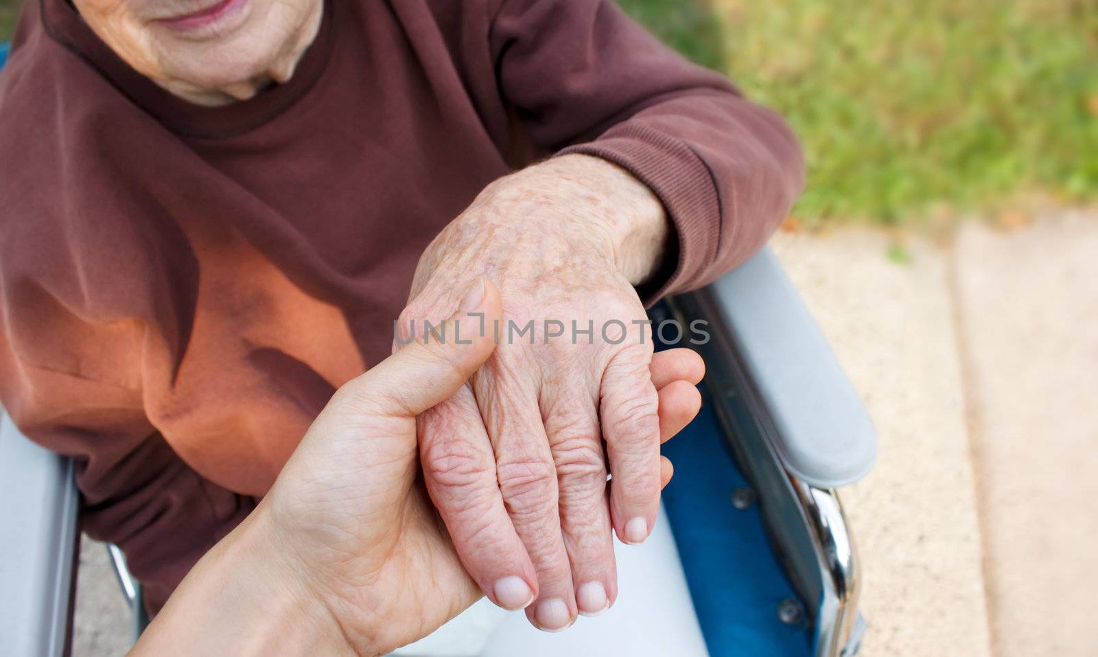Caregiver holding seniors hand in wheelchair