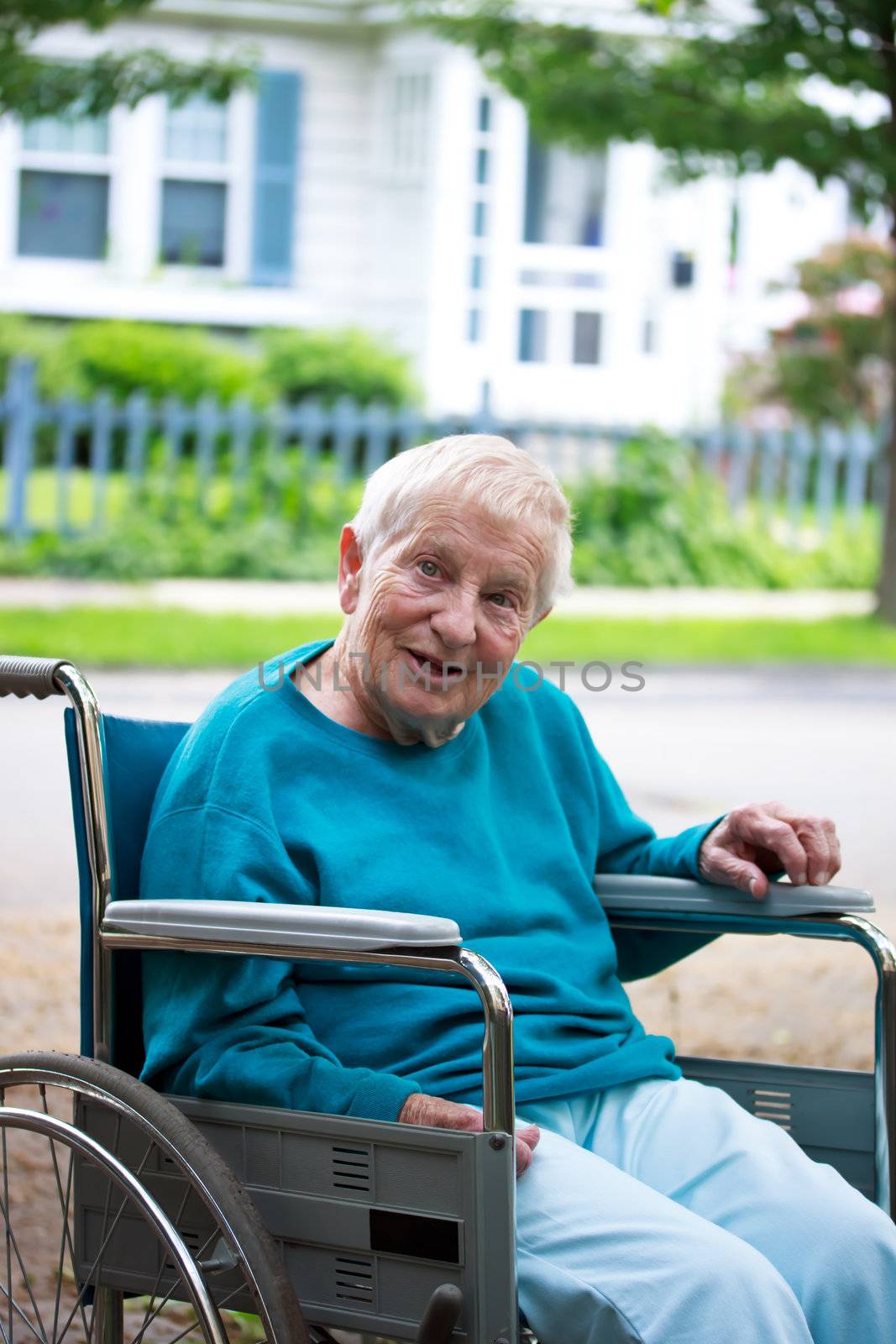 Happy senior lady in wheelchair in front of house