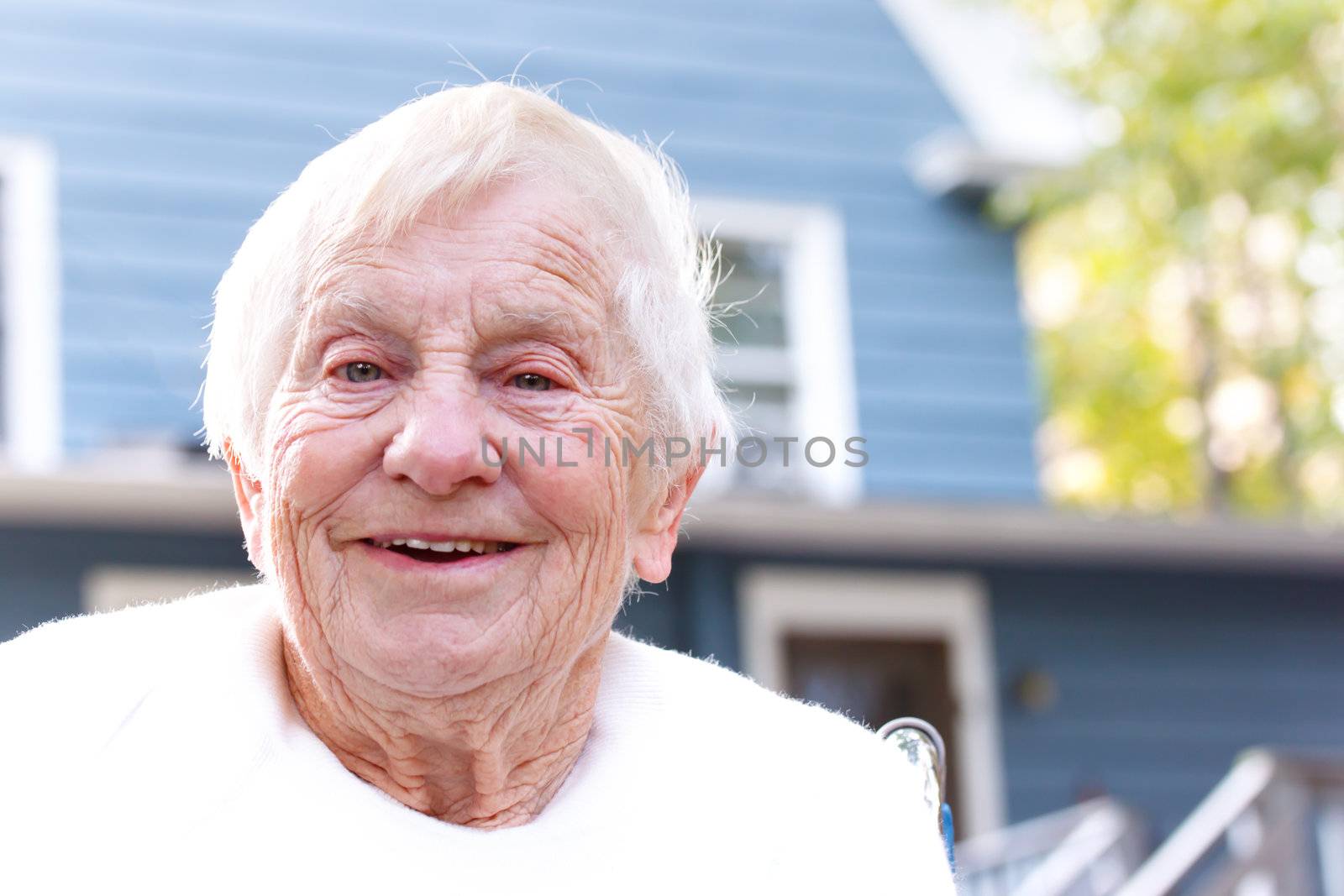 Happy senior lady in front of blue house