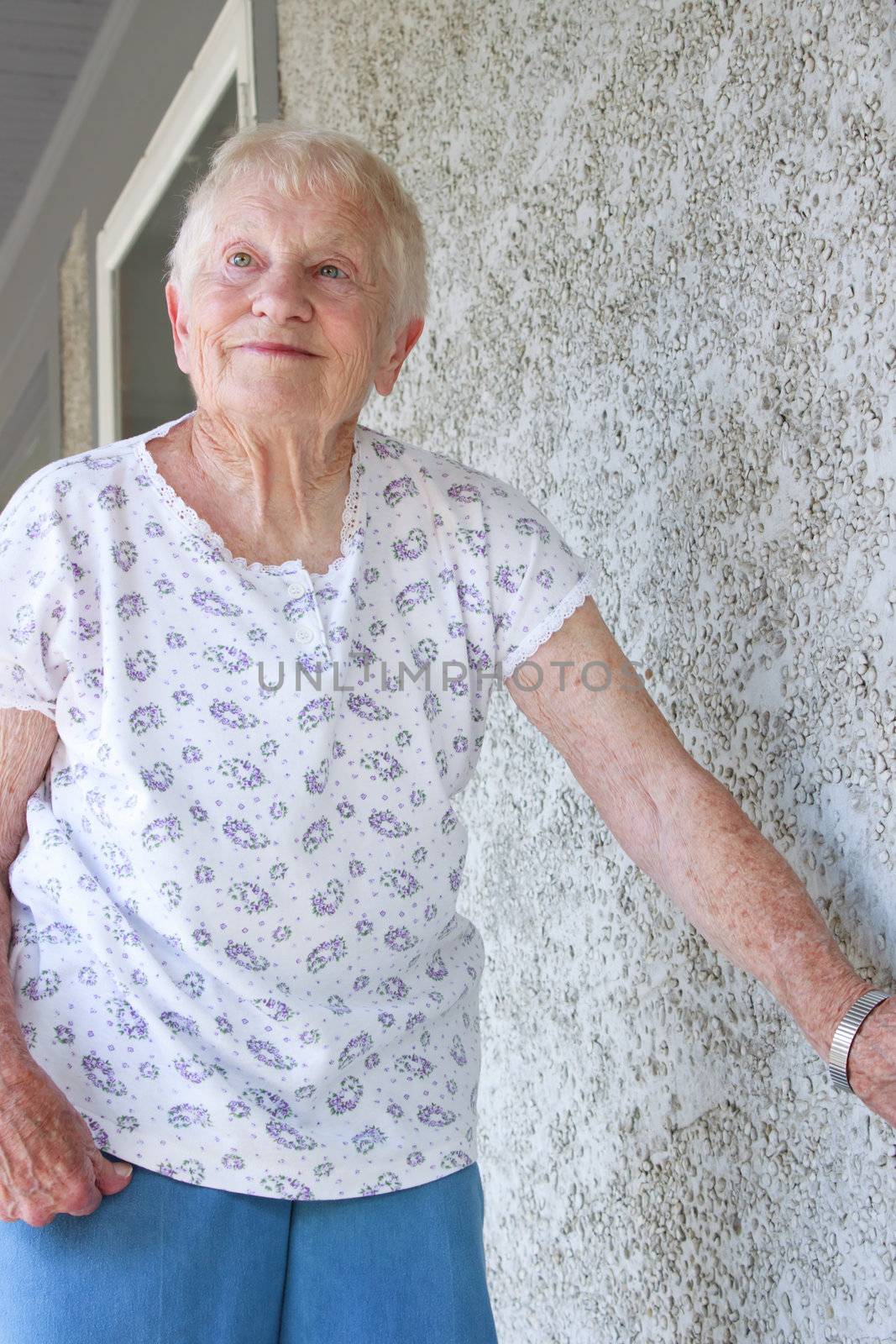 Happy senior lady standing on porch 