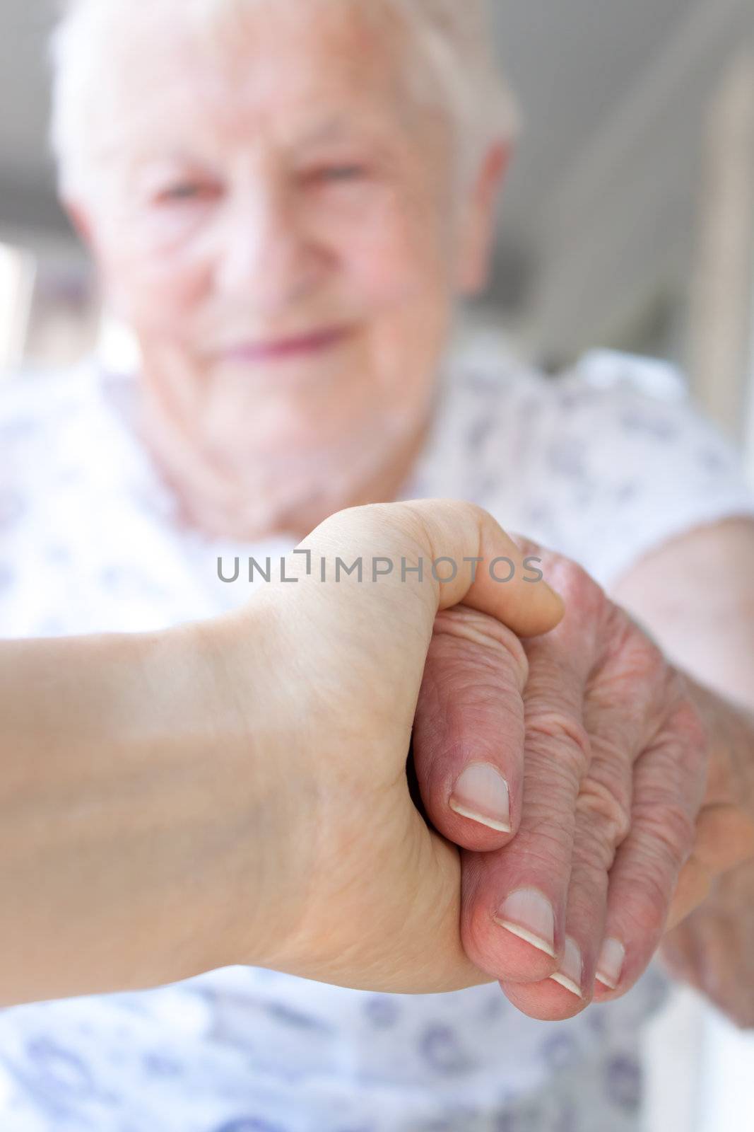 Young hand holding senior lady's hand by melpomene