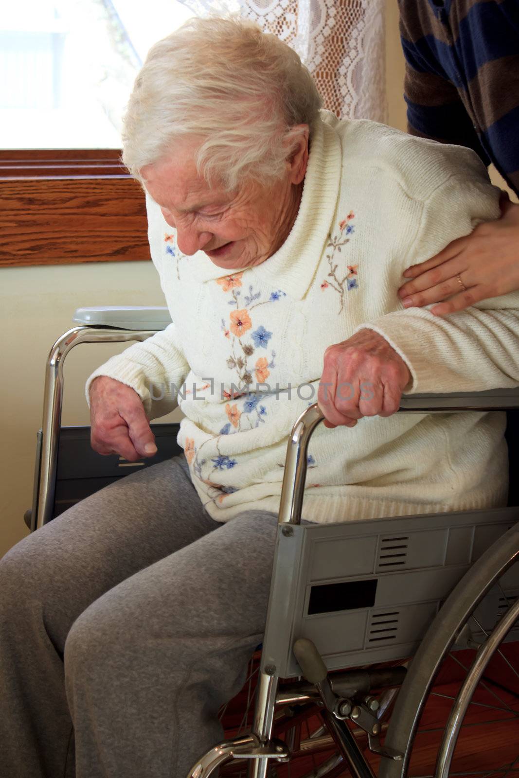 Caregiver helping senior lady get up from wheelchair