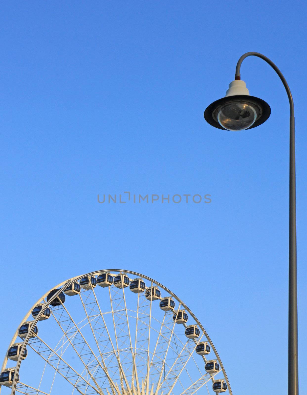 Street light with ferris wheel on blue sky