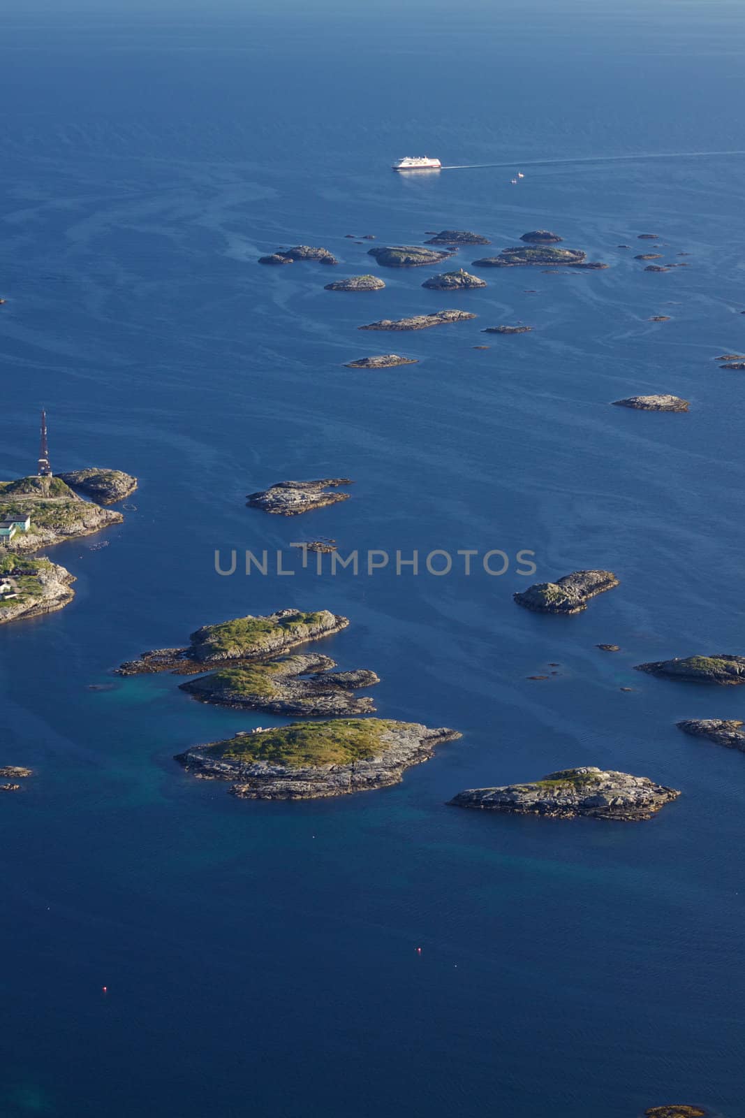 Large cruising ship passing by tiny islands on norwegian coast near town of Henningsvaer on Lofoten islands