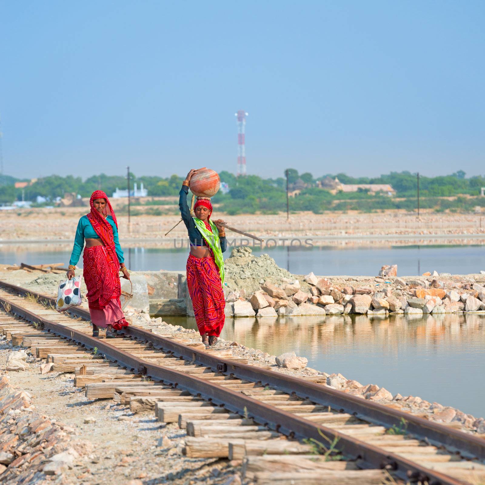 Sambhar, India - Nov 19: Female indian workers go along railway on Nov 19, 2012 in Sambhar Salt Lake, India. It is India's largest saline lake and and where salt has been farmed for a thousand years.