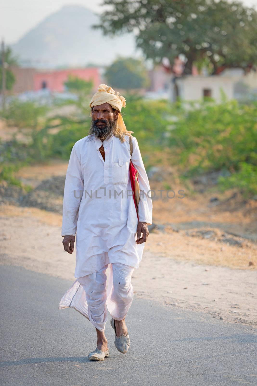 Sambhar, India - Nov 19: Indian countryman in traditional white cloth passes country road on Nov 19, 2012 in Sambhar Salt Lake, Rajasthan, India.