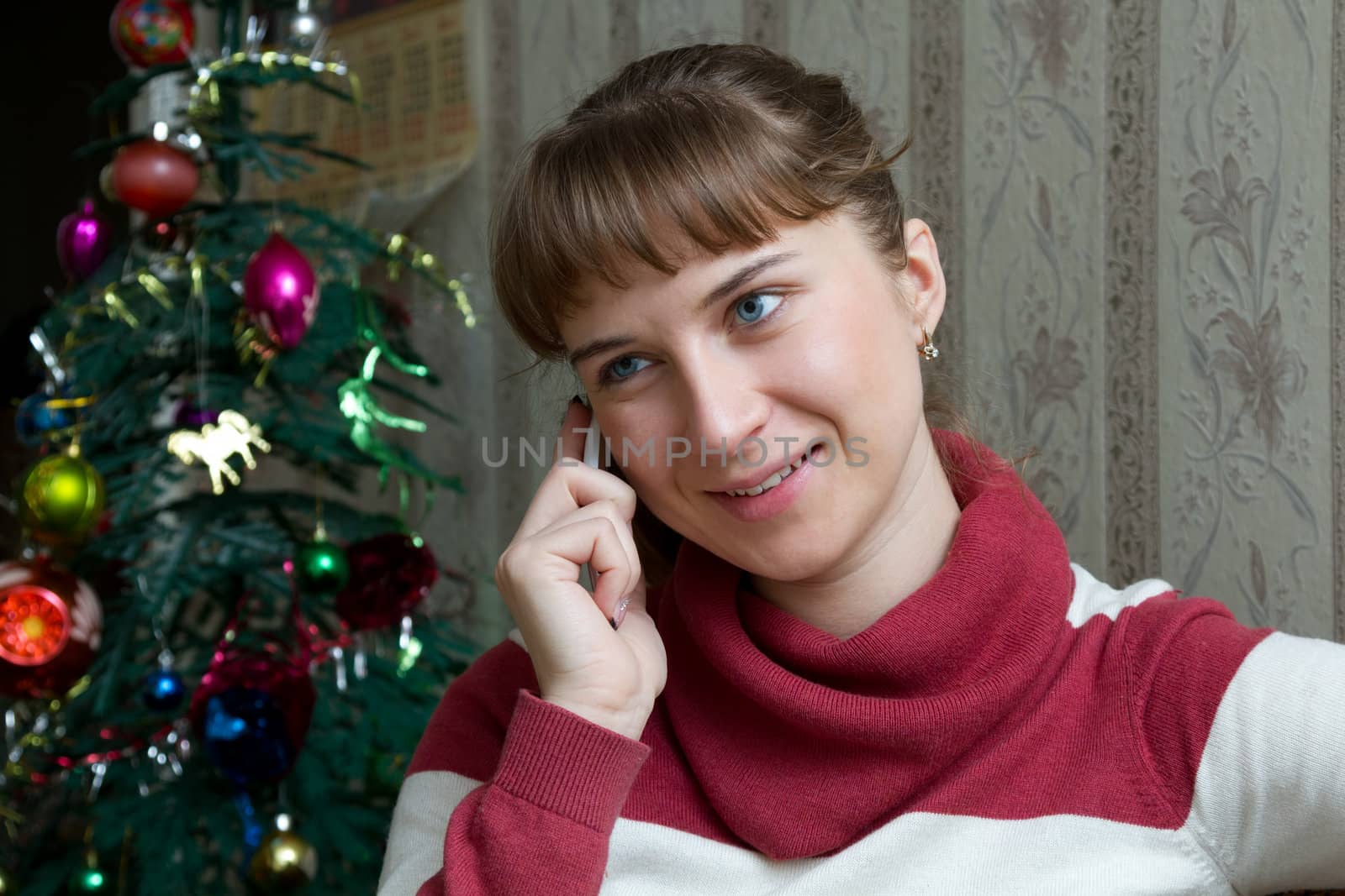 girl talking on the phone on the background of the Christmas tree
