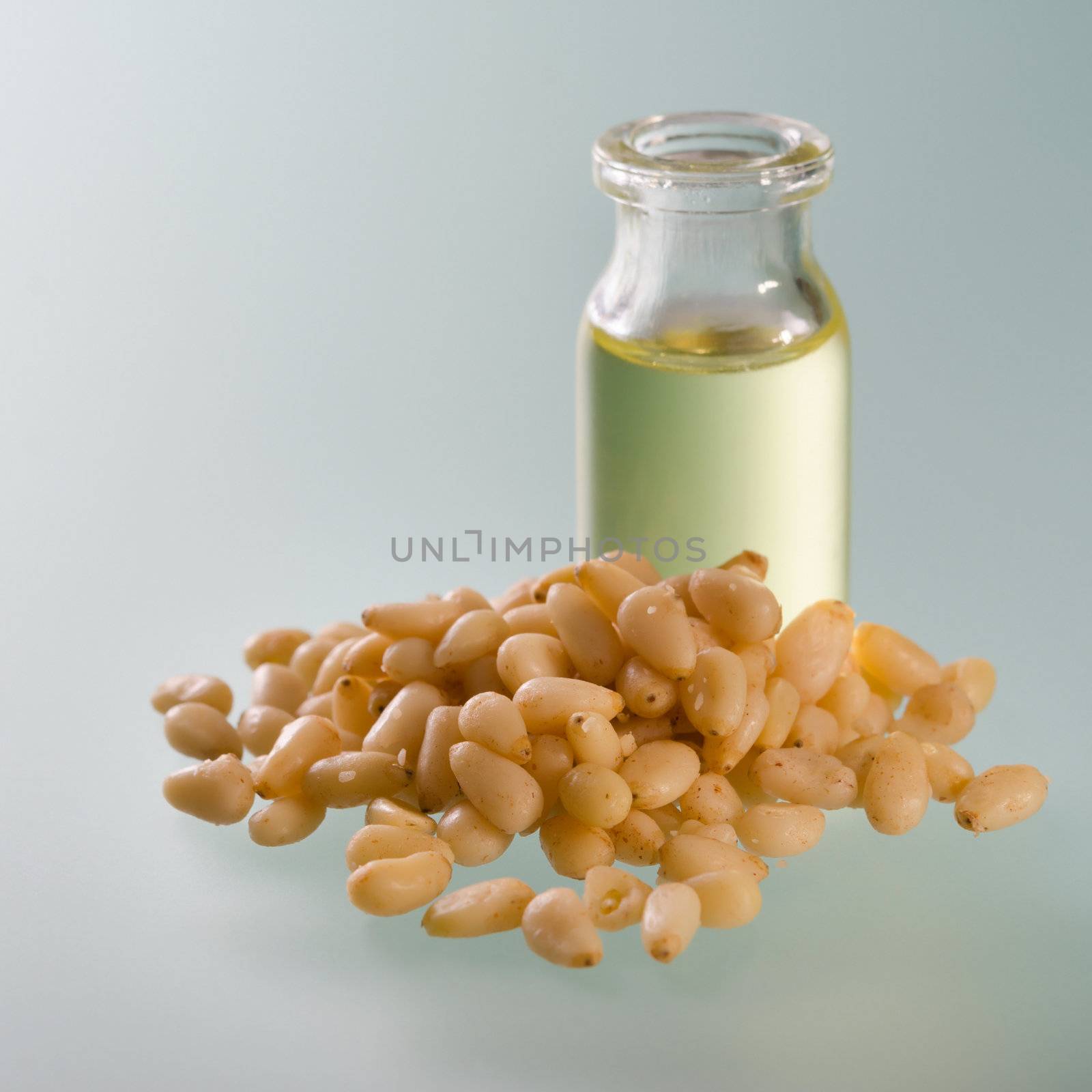 Open bottle of cedar oil and nuts on soft background
