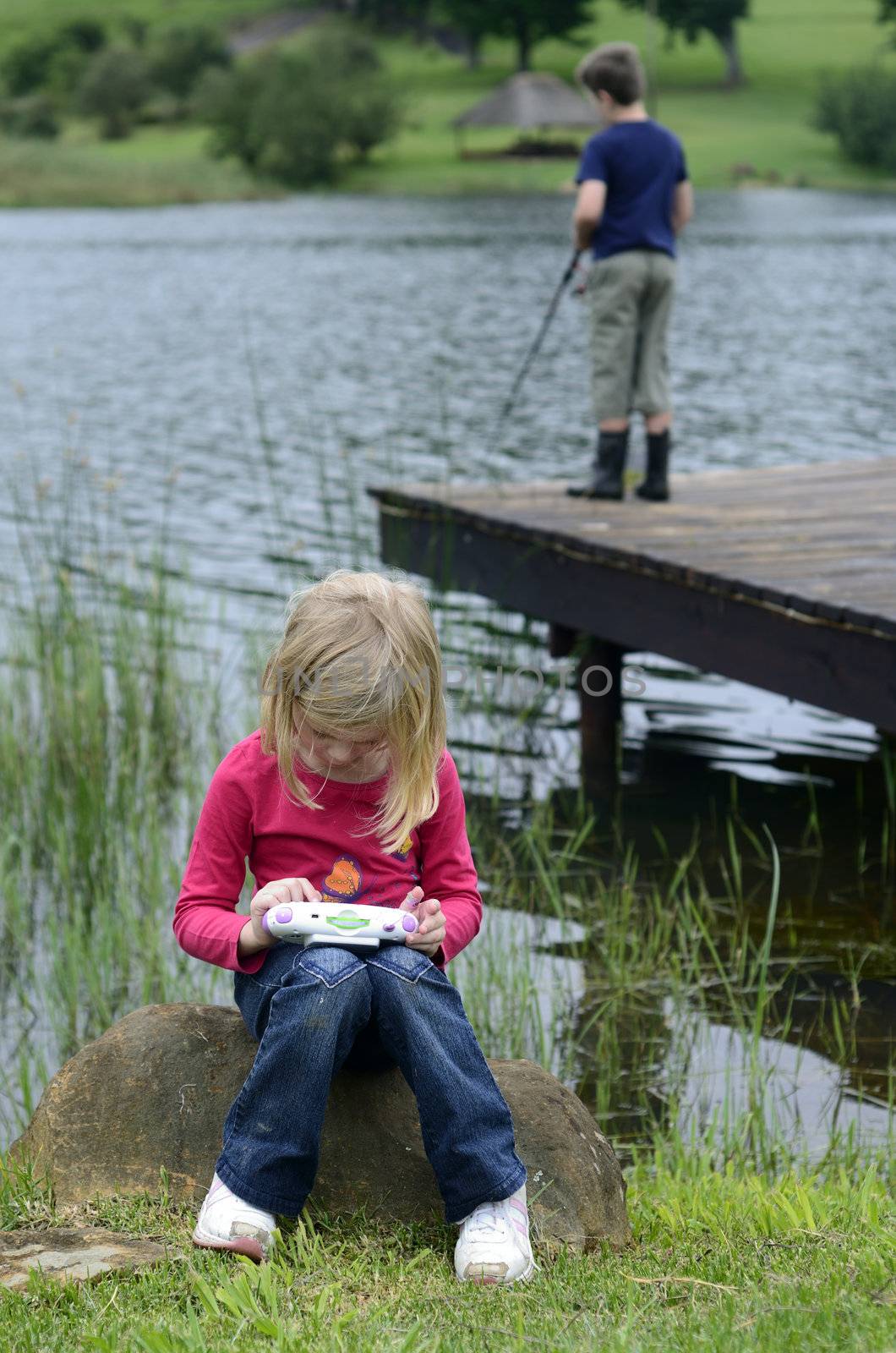 Young girl playing computer game in nature