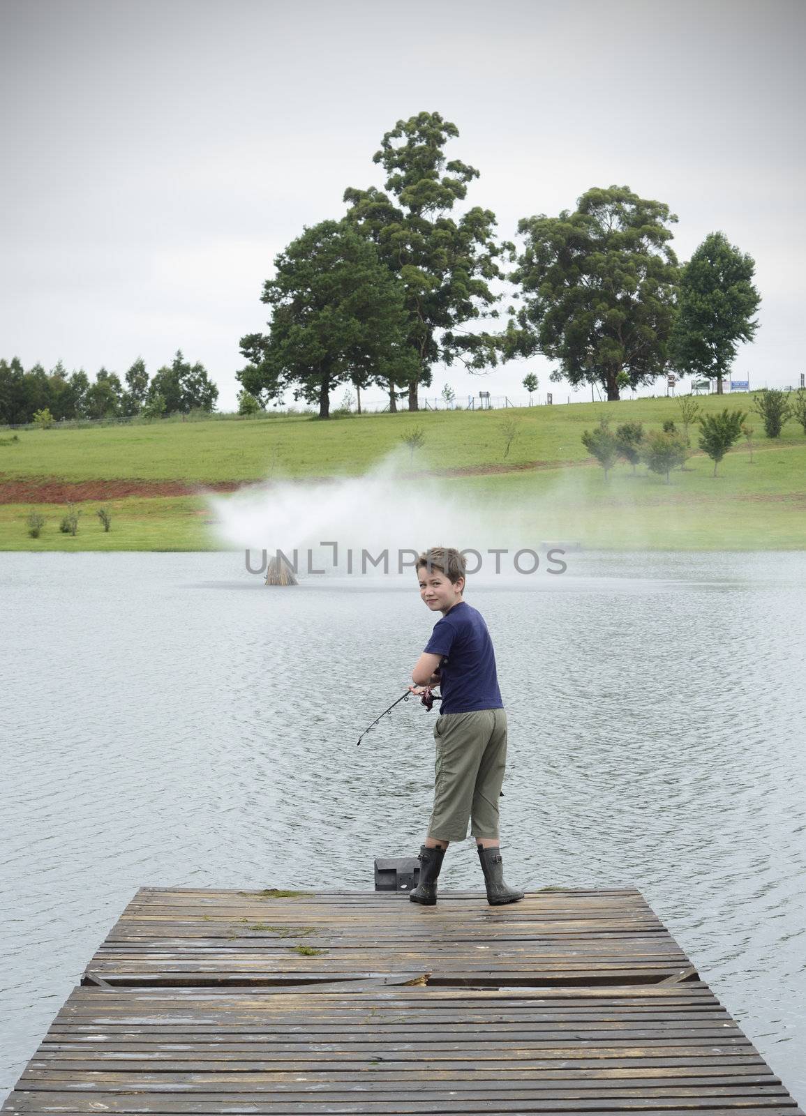 Boy bass fishing on dam or lake pier